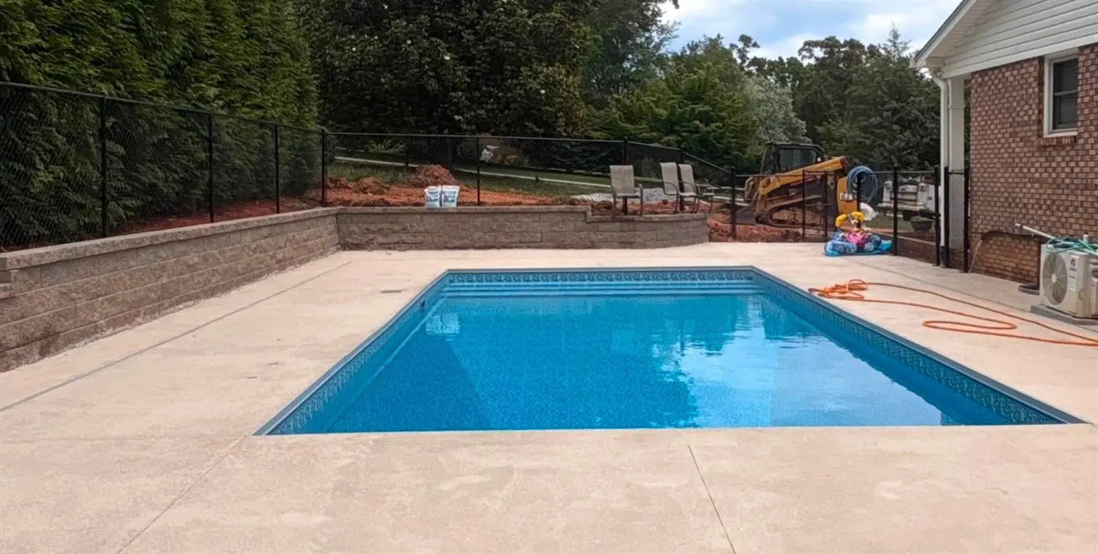 Finished pool with a block retaining wall holding the grade at the edge of the deck